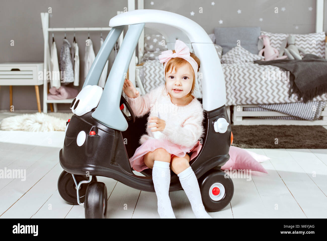 Wenig süßes, kleines Mädchen sitzt in einem spielzeugauto. Stockfoto