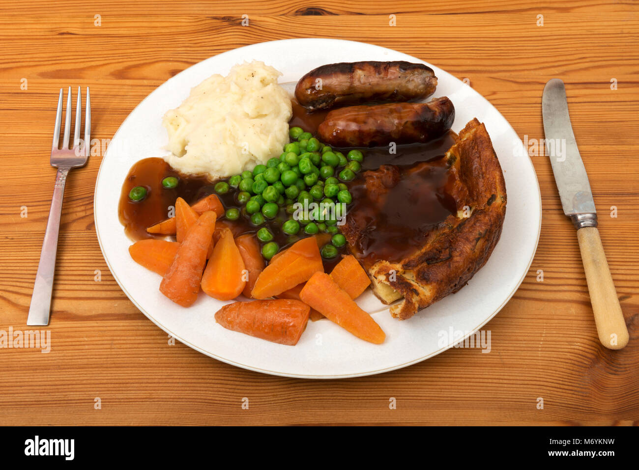 Traditionelle britische Abendessen Würstchen, Kartoffelpüree, Yorkshire Pudding mit Möhren und Erbsen. Stockfoto