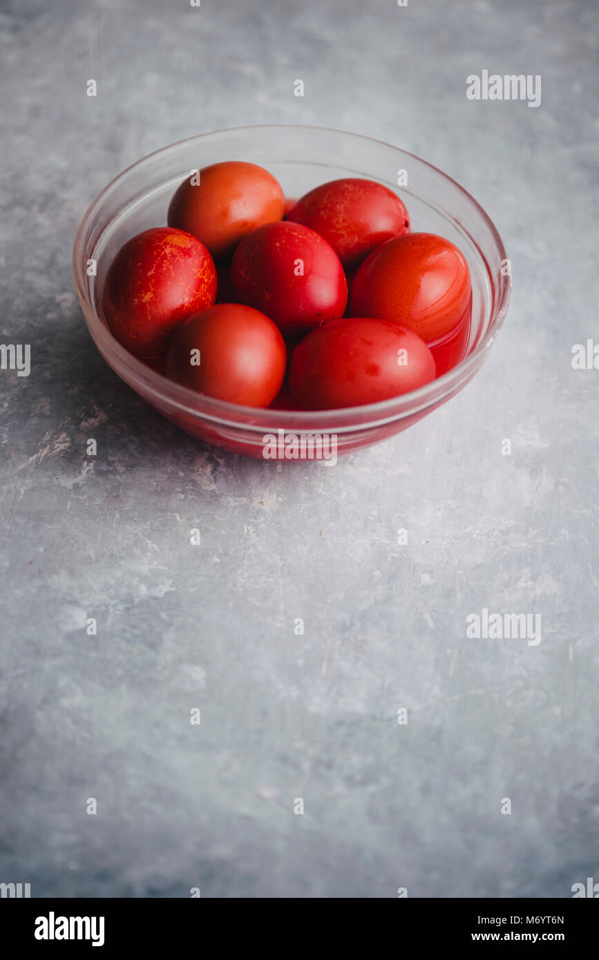 Satz von sechs Farben Rot, in eine Glasschale für Ostern, Färbung mit Rotstich Eier über einen konkreten Hintergrund, grau Stockfoto