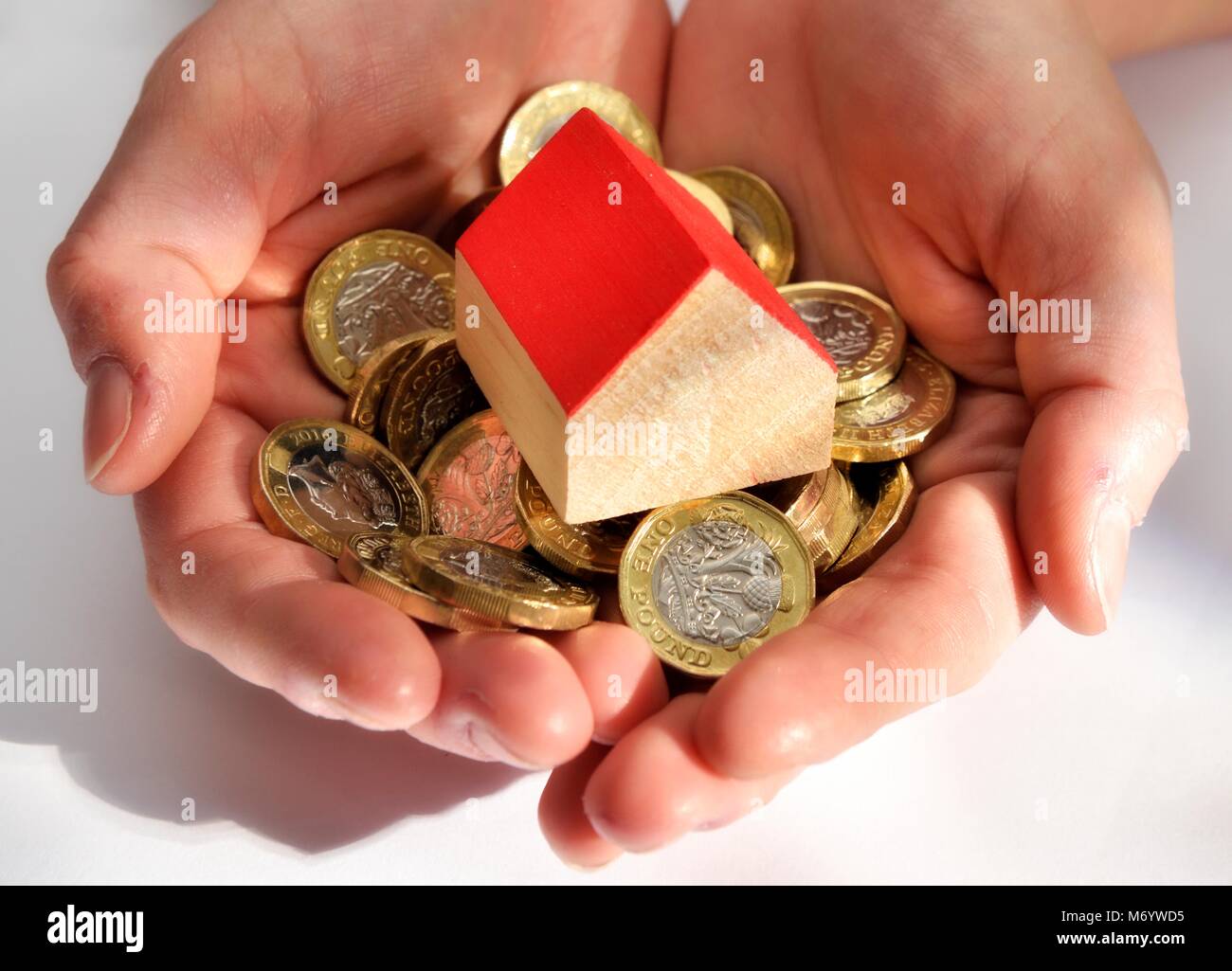 Handvoll ein Pfund Münzen und eine Miniatur Haus Geld Geld sparen Konzept Stockfoto
