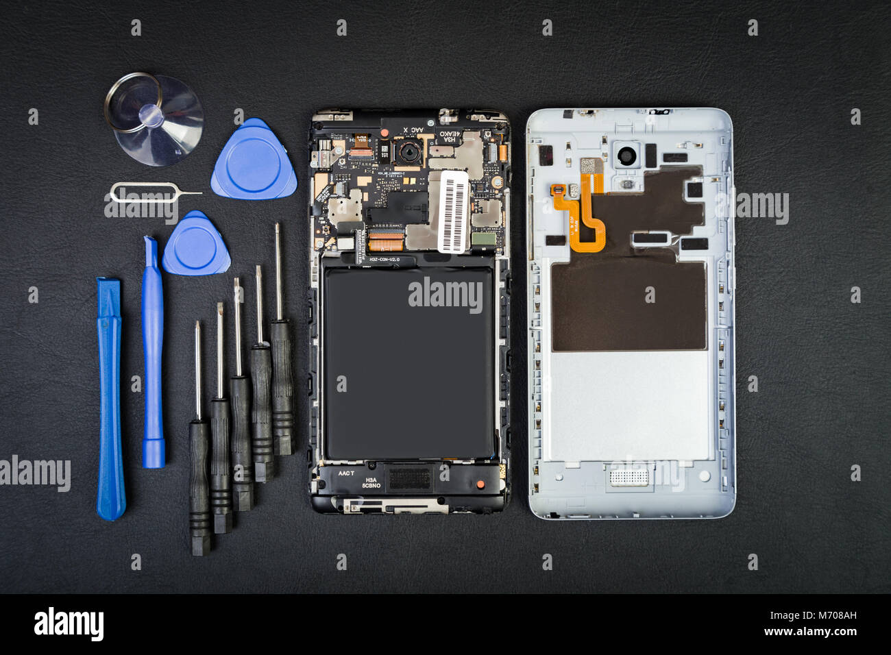 Arbeitsplatz der Handwerker mit den Telefon- und Sonderwerkzeuge auf dem Schwarzen Tisch. Zerlegt Smartphone in flatlay Stil. Stockfoto