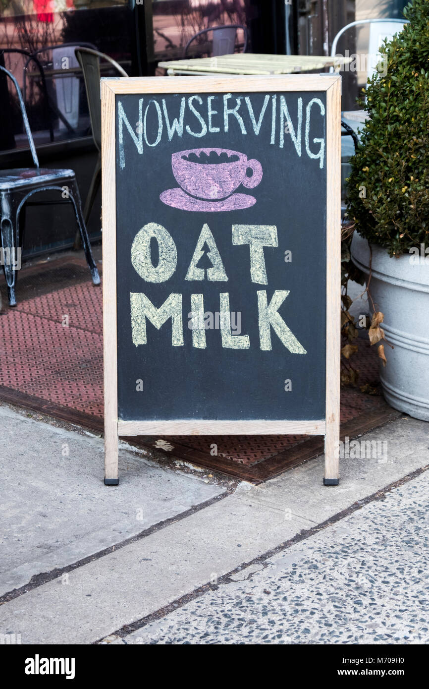 Ein Zeichen auf einer Tafel vor einem Café in Manhattan, Hafermilch verfügbar ist. Stockfoto