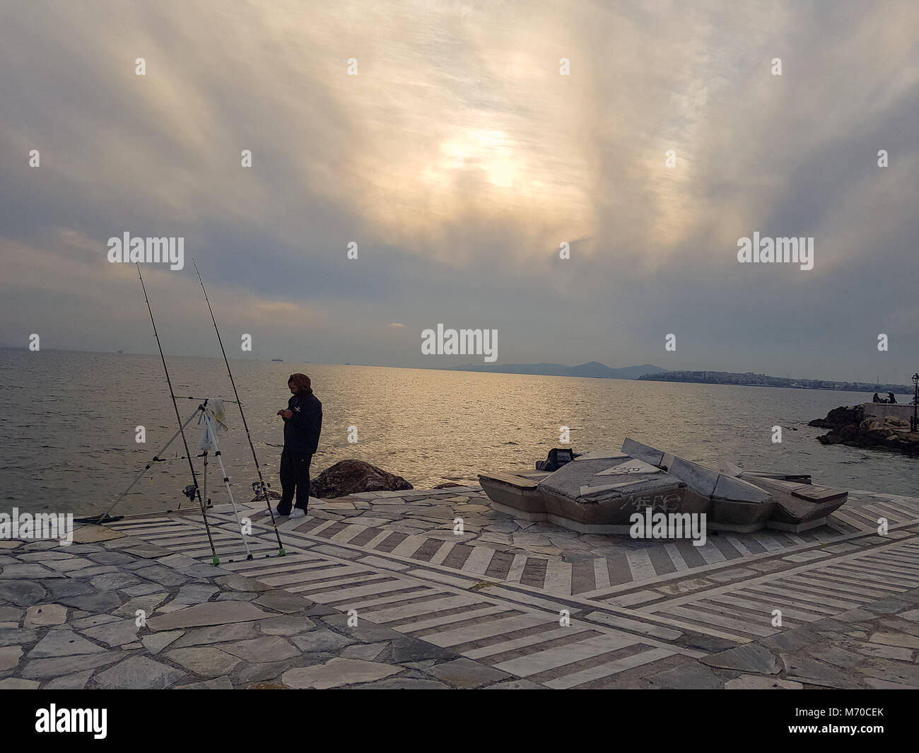 Athen, Griechenland - 18. Februar 2018: Mann stand in der Nähe von unbeaufsichtigten Angelruten an der Promenade von Palaio Faliro in Athen, Griechenland Stockfoto