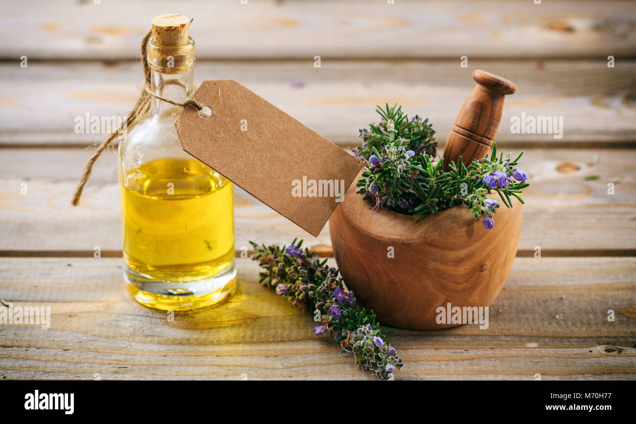 Rosemary wesentliches Öl und frischen blühenden Zweig in einem hölzernen Mörtel, Holztisch, leeres Tag, Platz für Text Stockfoto