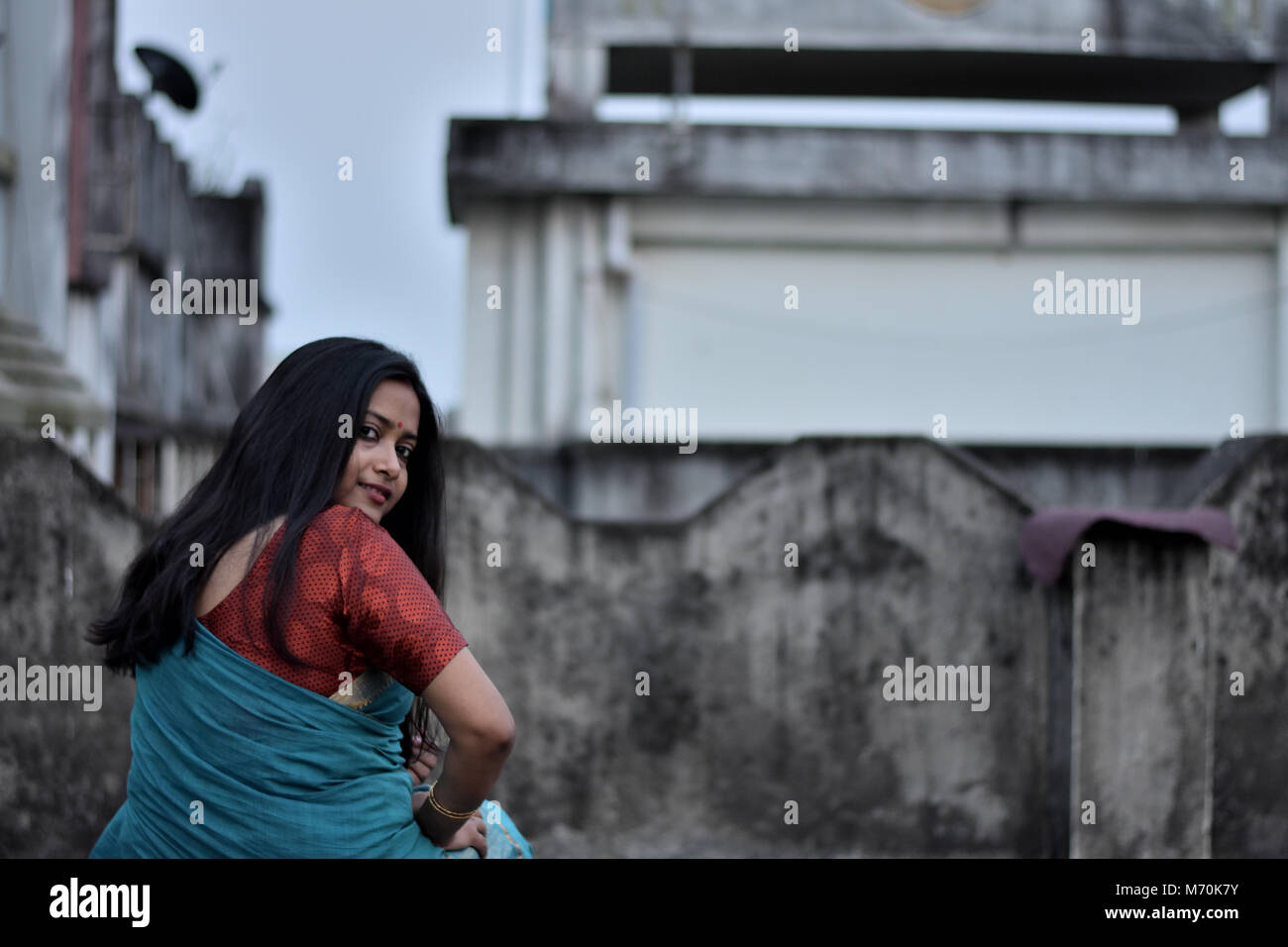 Schöne Bengali Mädchen dreht ihren Kopf nach hinten zu schauen, während das Sitzen auf der Dachterrasse Stockfoto