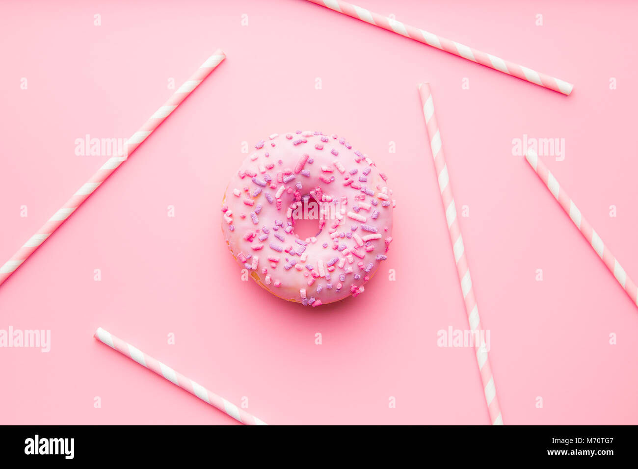 Rosa Donut und rosa Strohhalme auf rosa Hintergrund. Stockfoto