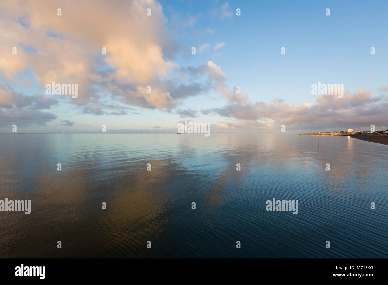 Schönes Licht und grosse orange Wolken in einem noch, spiegelglatte Meer in Richtung Herne Bay von Hampton Pier, Kent, Großbritannien Suche wider. Stockfoto