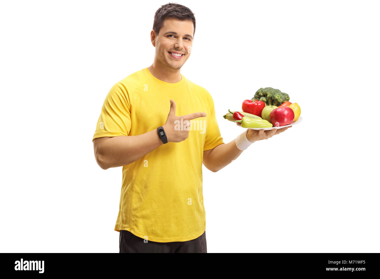 Junge Mann hält einen Teller mit Obst und Gemüse und zeigen auf weißem Hintergrund Stockfoto
