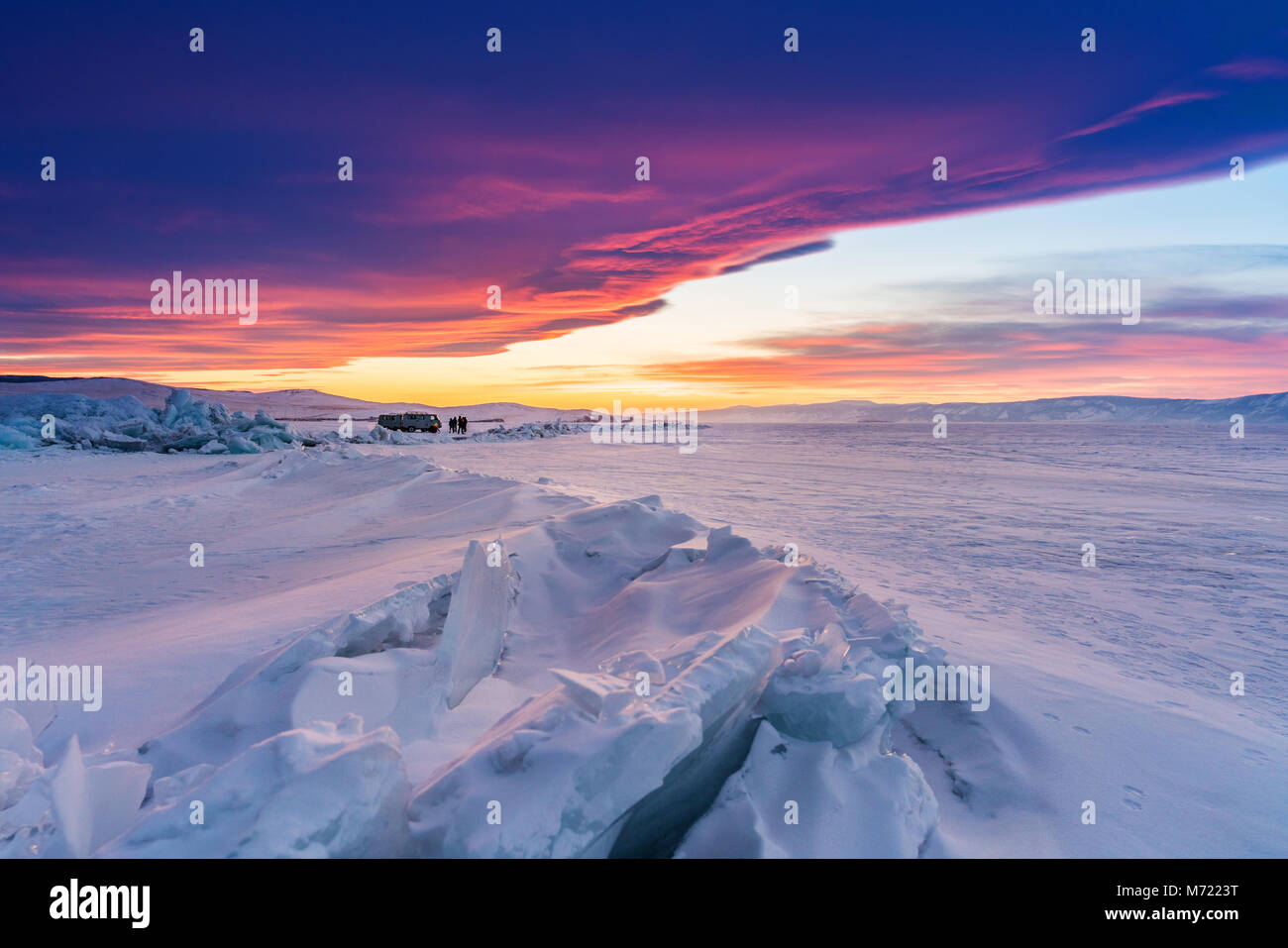 Winterlandschaft im Sonnenuntergang, gerissene gefrorenen See bedeckt von Schnee am Baikalsee in Russland mit schönen Sonnenuntergang Himmel Stockfoto