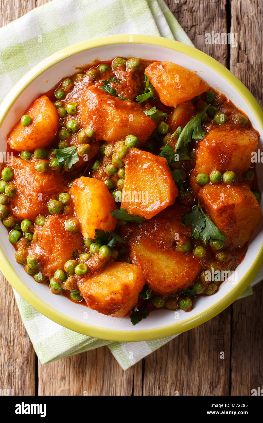 Würzige Aloo Matar Kartoffeln, grüne Erbsen und Gewürze close-up auf einem Teller. Vertikal oben Ansicht von oben Stockfoto