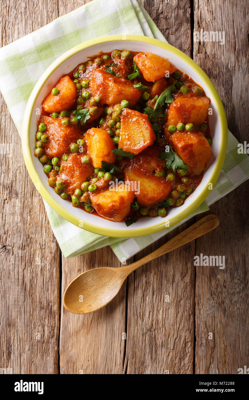 Home indisches Essen: aloo Matar - Kartoffeln, grüne Erbsen und pikanter Sauce closeup auf einem Teller. Vertikal oben Ansicht von oben Stockfoto
