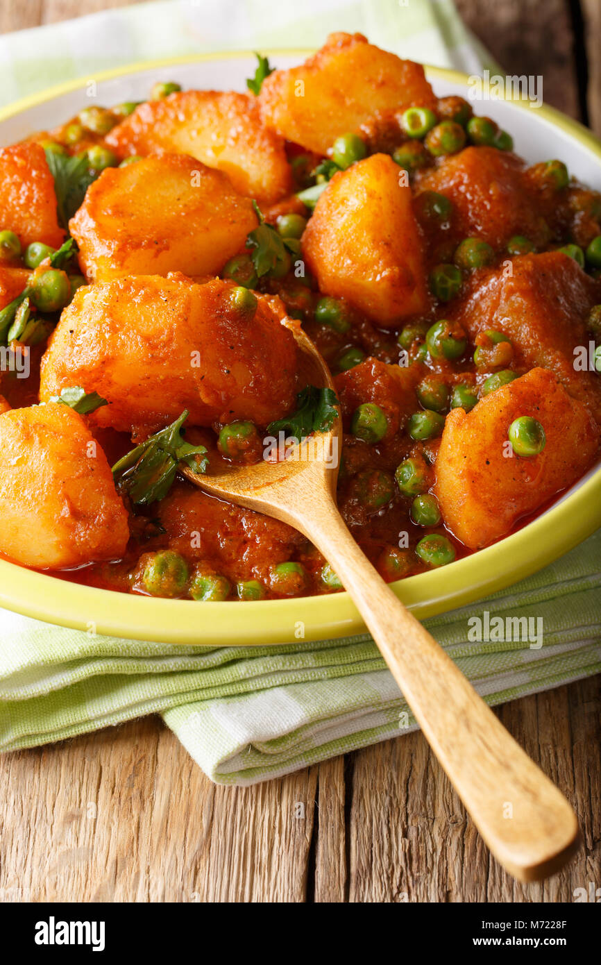 Indische Küche: aloo Matar aus Kartoffeln und grünen Erbsen close-up auf einem Teller auf dem Tisch. Vertikale Stockfoto