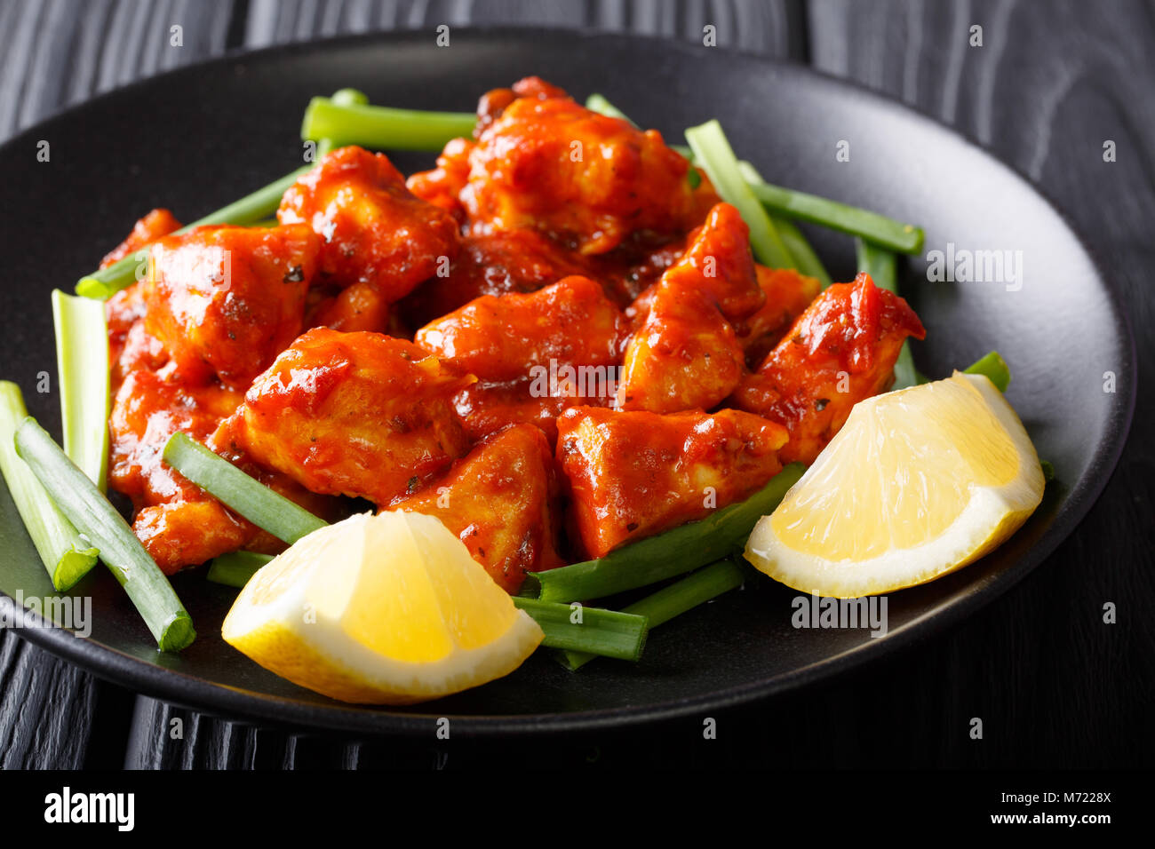 Stir Fry Chicken mit heißer Soße, grüne Zwiebeln und Zitronensaft close-up auf einem Teller auf den Tisch. Horizontale Stockfoto
