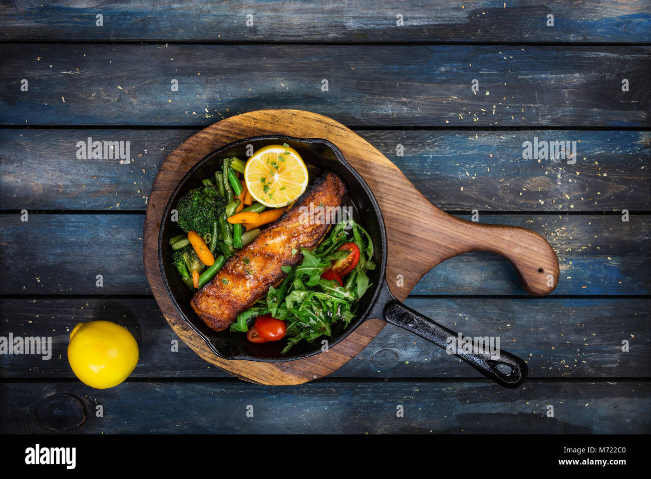 Gegrilltes Lachsfilet in einer Pfanne, Gemüse, Rucola mit Zitrone. Stockfoto