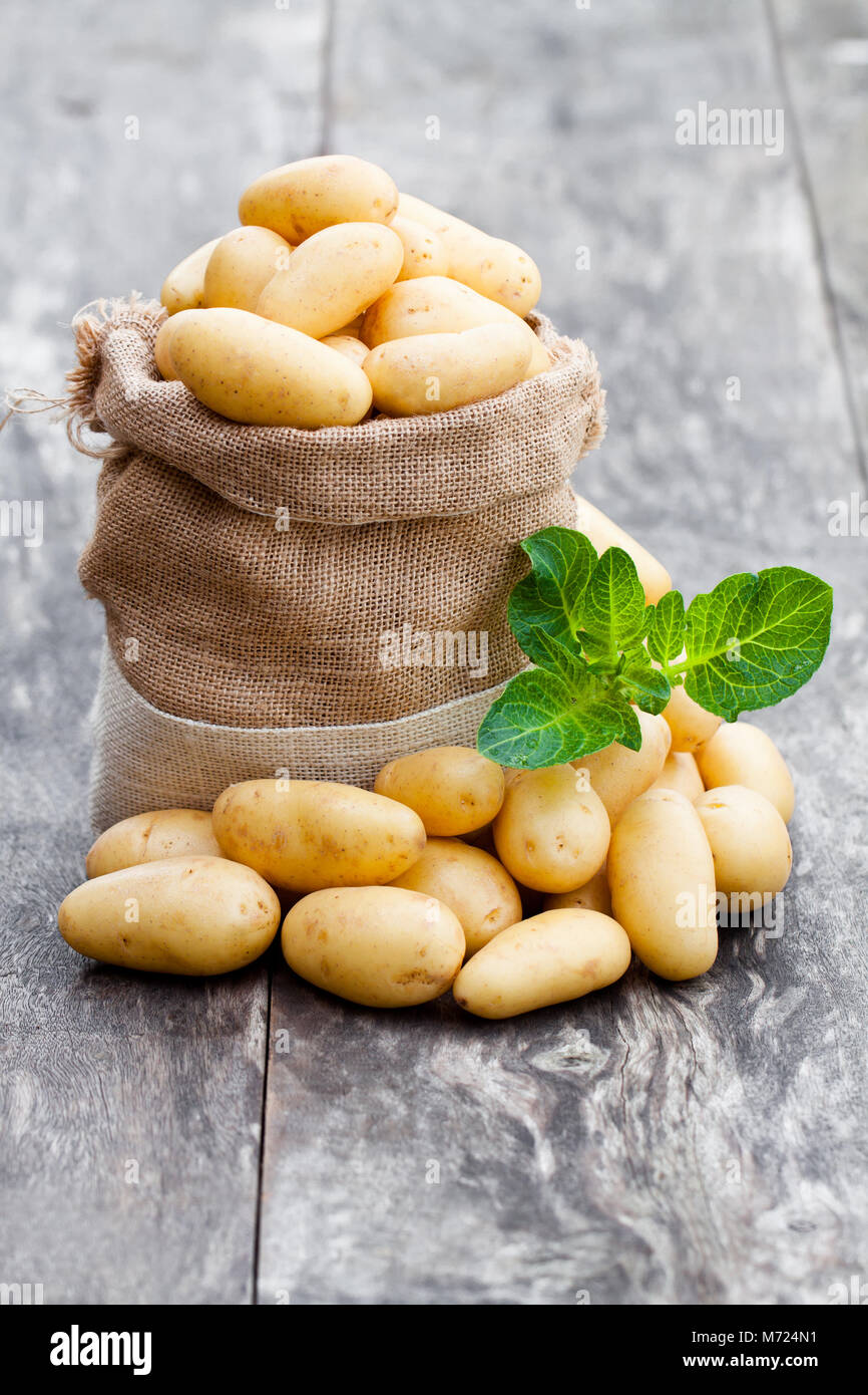 Baby Kartoffeln in sackleinen Sack auf Holz- Hintergrund Stockfoto