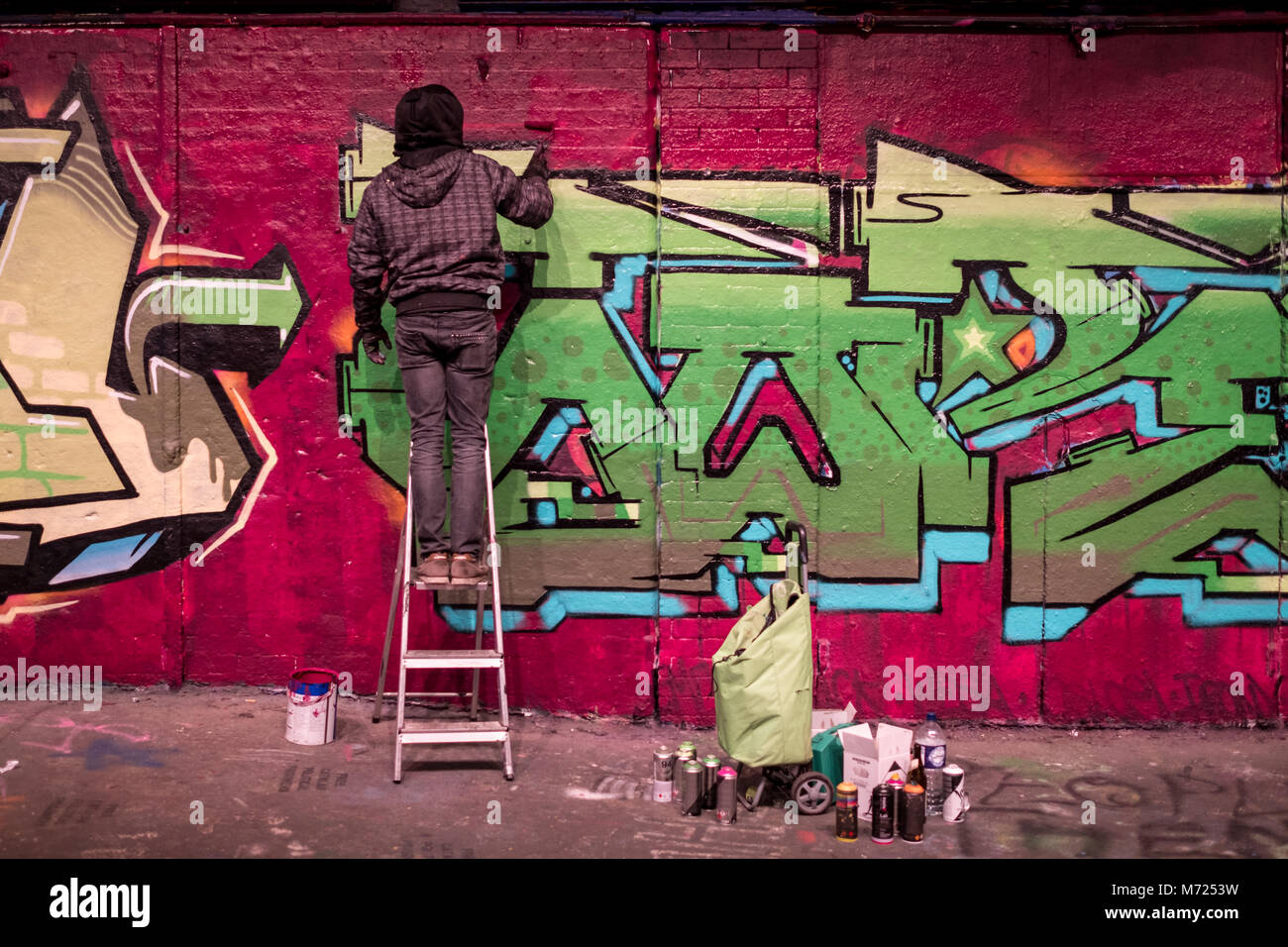 Man steht auf einer Leiter, Graffiti, Leake Street, London, in der Nähe der Waterloo Station. Stockfoto