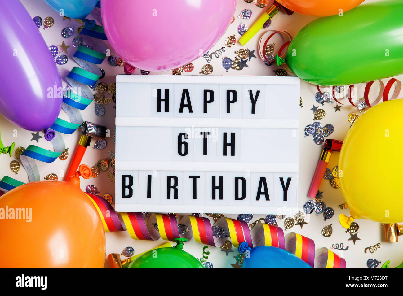 Glücklich 6. Geburtstag Feier Nachricht auf ein Leuchtpult mit Ballons und Konfetti Stockfoto