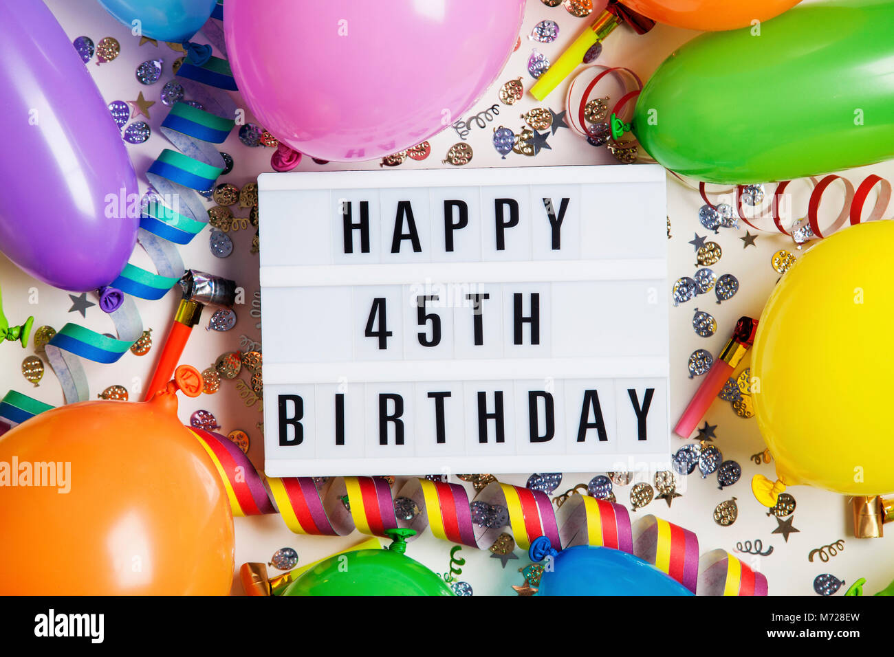 Happy 45th birthday celebration Nachricht auf ein Leuchtpult mit Ballons und Konfetti Stockfoto