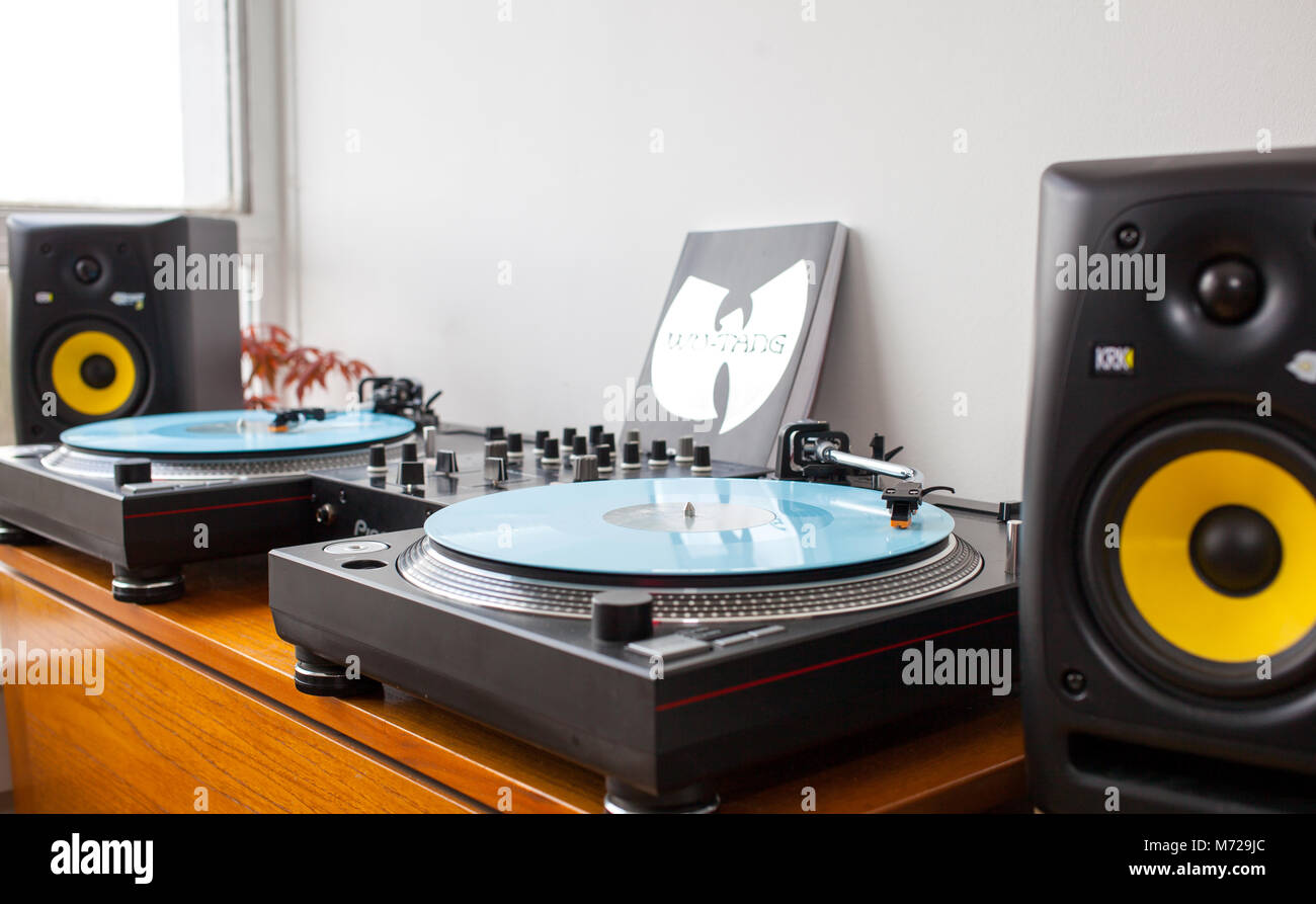 Ein DJ-Set-up mit zwei Turntables, Mischpult und Lautsprecher. Wu-Tang Handbuch Buch lehnte sich an der Wand. Alle auf Holz- gefaltet Tabelle. Rote Pflanze im Hinterg Stockfoto