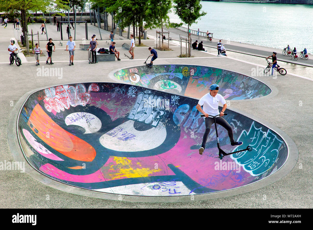 Junge, Mid-air scooter Trick in bunten Skatepark Bowl, Lyon, Auvergne-Rh ône-Alpes, Frankreich Stockfoto