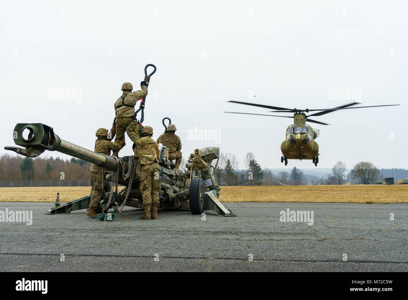 Eine CH-47 Chinook Hubschrauber Besatzung zu Unternehmen B zugeordnet sind, 2. Allgemeine Unterstützung Aviation Battalion, 227 Aviation Regiment, 1 Combat Aviation Brigade, 1.Kavallerie Division, bereitet in Position über artilleristen mit Batterie B, Field Artillery Squadron, 2.Kavallerie Regiments, mit Schlinge legen Sie ein M777 Haubitze während der Proben auf einem Flugplatz in der Nähe von Grafenwöhr, Deutschland März 6, 2018. Soldaten der beiden Einheiten kamen zusammen, um Beziehungen zu Schulen und bei der dynamischen Front 18, eine jährliche US-Army Europe Übung zur Verbesserung der Interoperabilität der US-Armee, gemeinsamen Dienst stärken und Alliierten Stockfoto