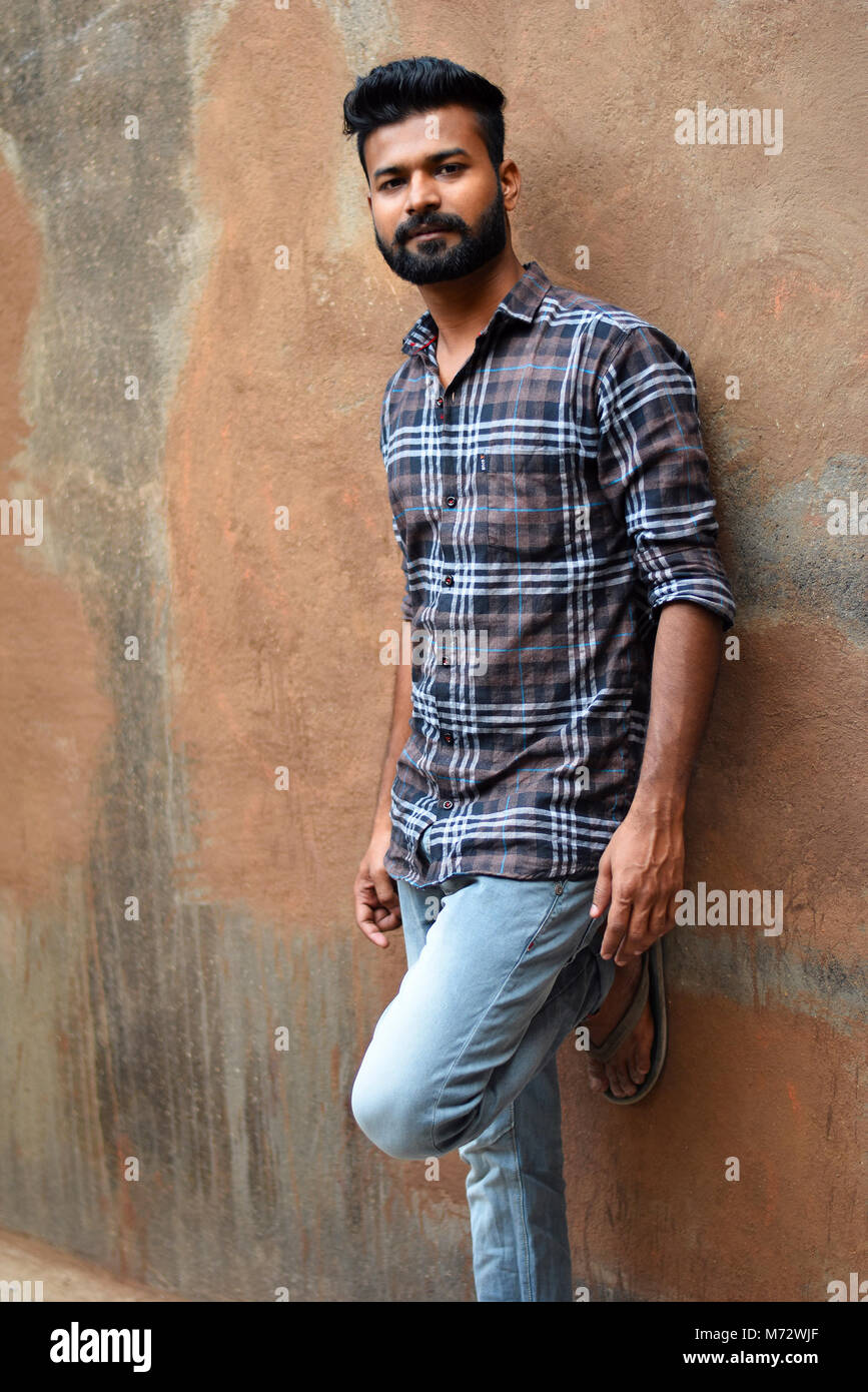 Männliches Modell auf Kamera mit Bein gegen die Wand. Mumbai, Maharashtra Stockfoto