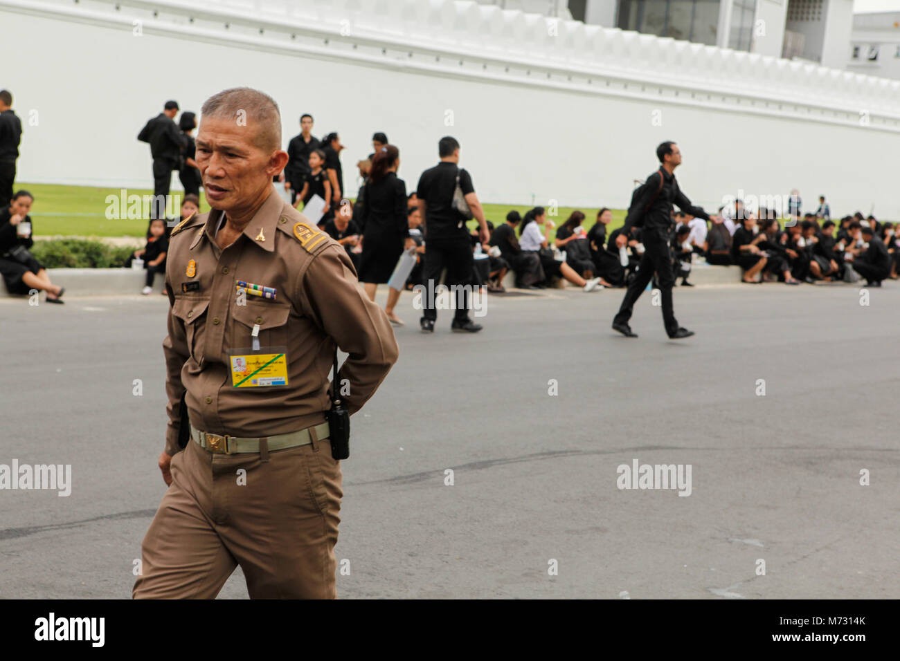 Eine thailändische Armee Offizier Spaziergänge in der Straße vor dem weißen Wände des Grand Palace in Bangkok, unter den Menschen in Trauer tragen schwarze Kleidung Stockfoto