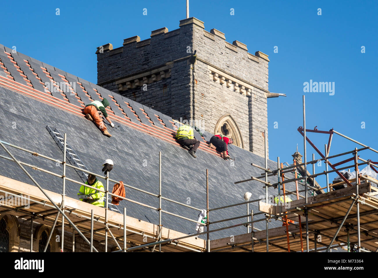 Zur Festsetzung der Dach, während die Sonne scheint. Das satteldach aller Heiligen Kirche in Barry, Wales auf einem hellen, sonnigen Tag unter einem blauen Himmel repariert wird Stockfoto