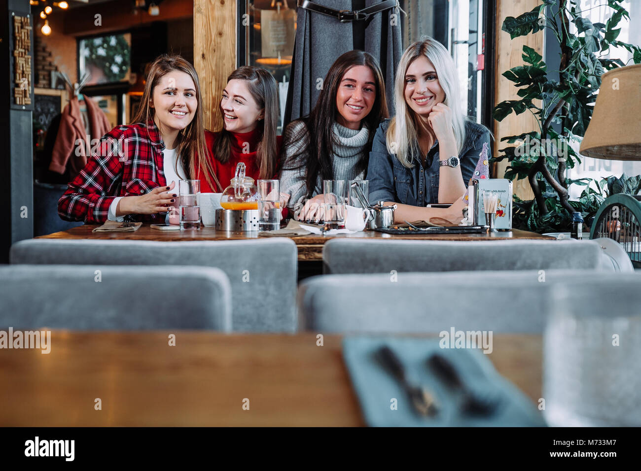 Vier Freunde im Cafe Blick in die Kamera und Lachen Stockfoto