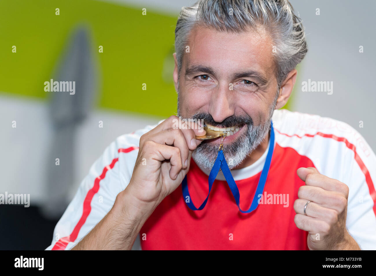 Mann beißt die Goldmedaille. Stockfoto