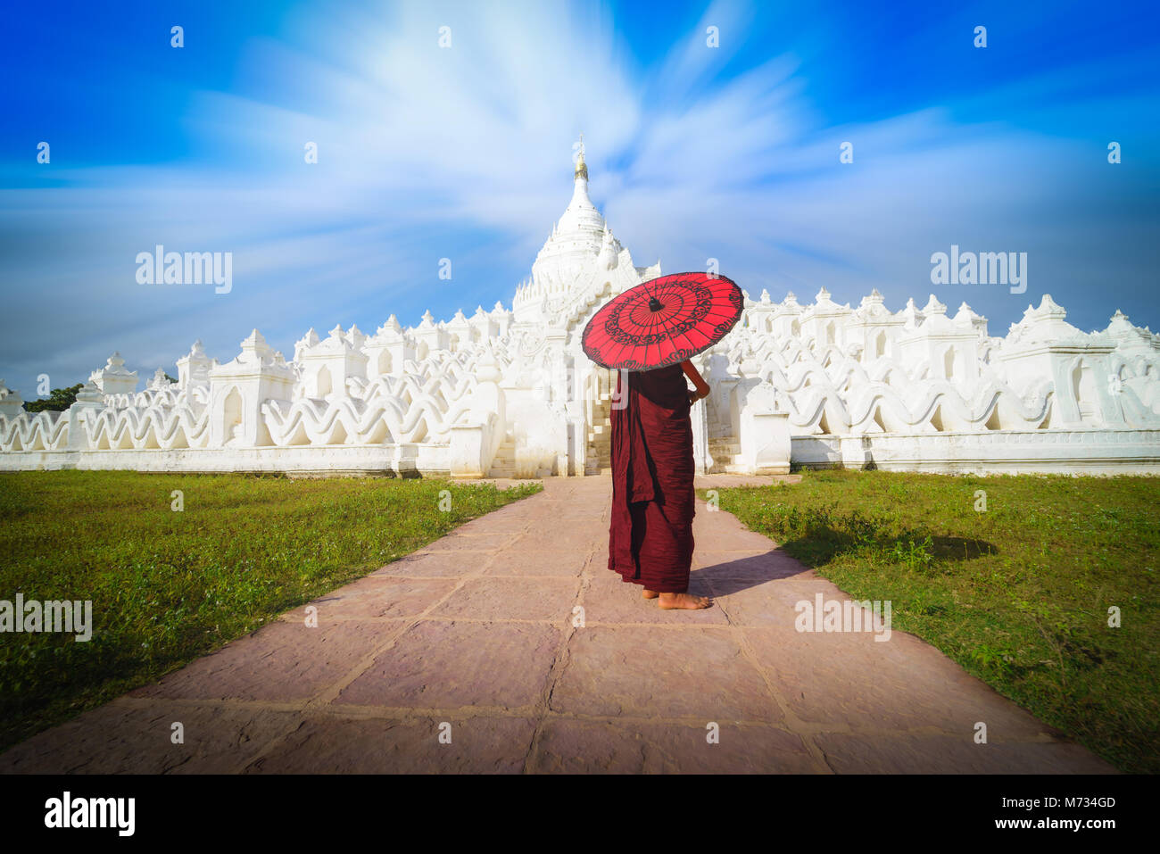Asiatische junge Mönch halten roten Sonnenschirme am blauen Himmel in der Mya Thein Tan Mingun Pagode in Mandalay, Myanmar. Stockfoto
