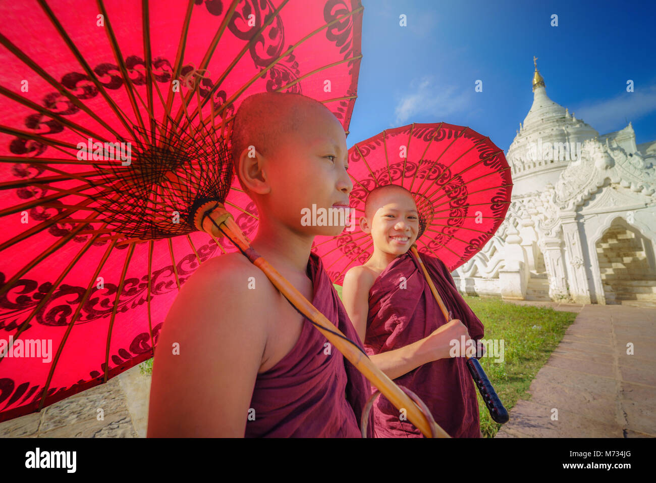MANDALAY, Myanmar, - Dezember 11, 2017: Nicht identifizierte zwei Asiatische junge Mönch halten roten Sonnenschirme am Mya Thein Tan Pagode in Mandalay Mingun, Myanma Stockfoto