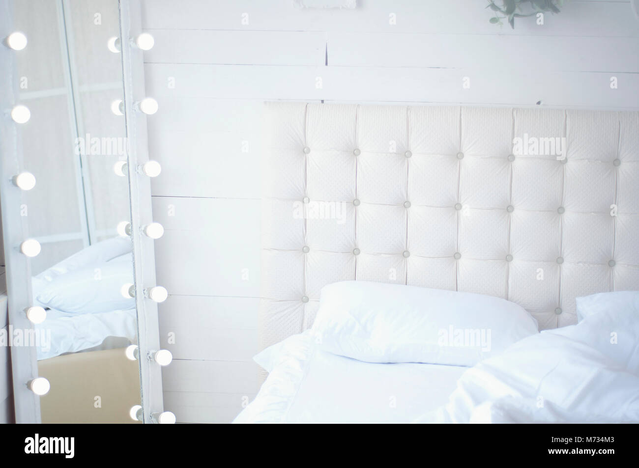 Strauß Blumen auf dem Bett und einem Spiegel mit Glühlampen Stockfoto