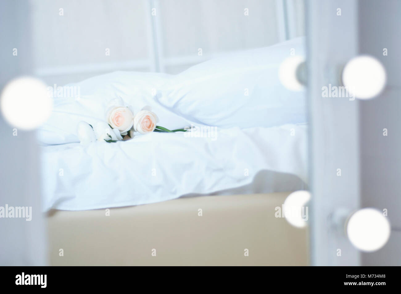 Strauß Blumen auf dem Bett und einem Spiegel mit Glühlampen Stockfoto