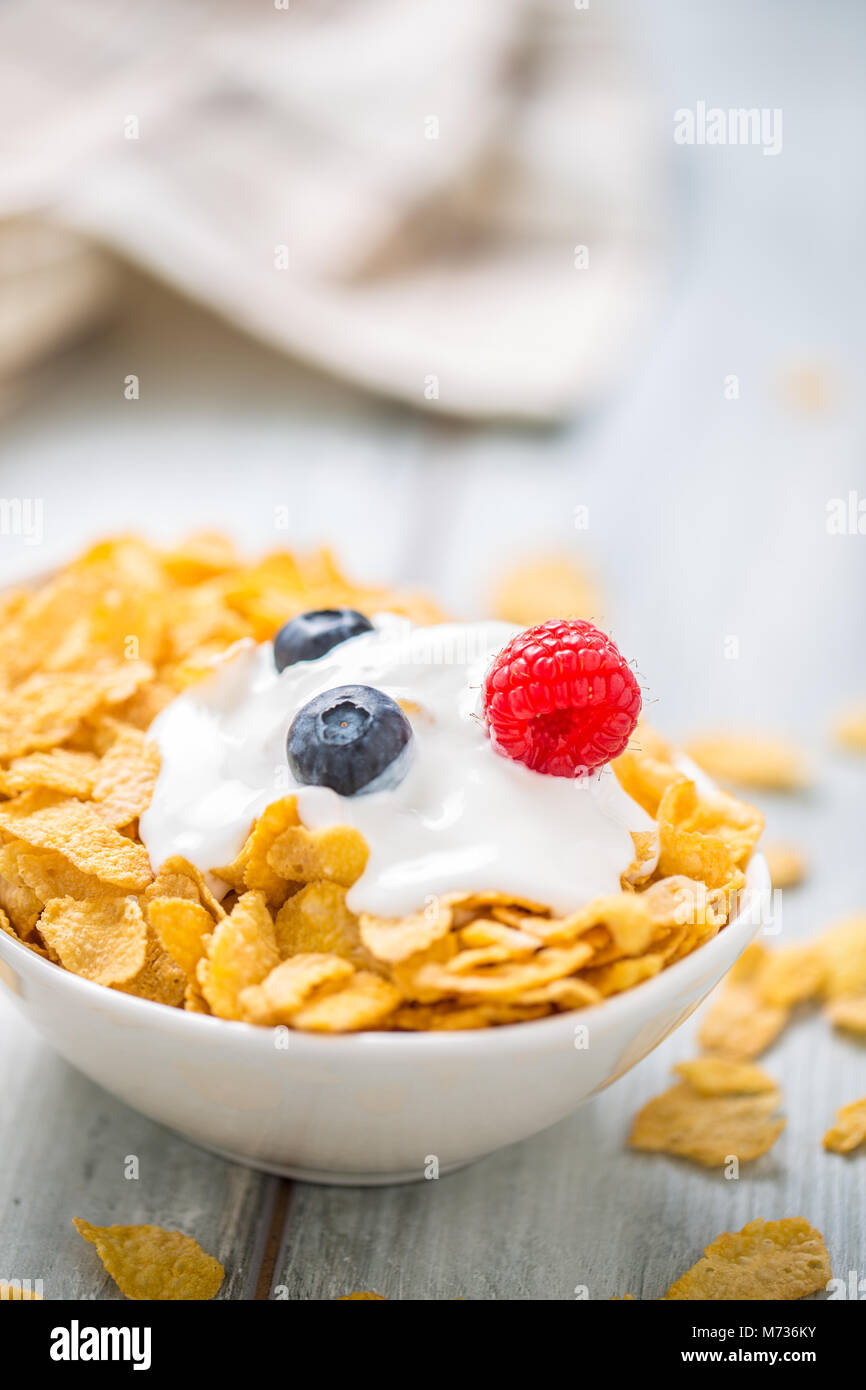 Cornflakes. Schüssel Cornflakes mit Joghurt Heidelbeeren und Himbeeren am Küchentisch Stockfotografie