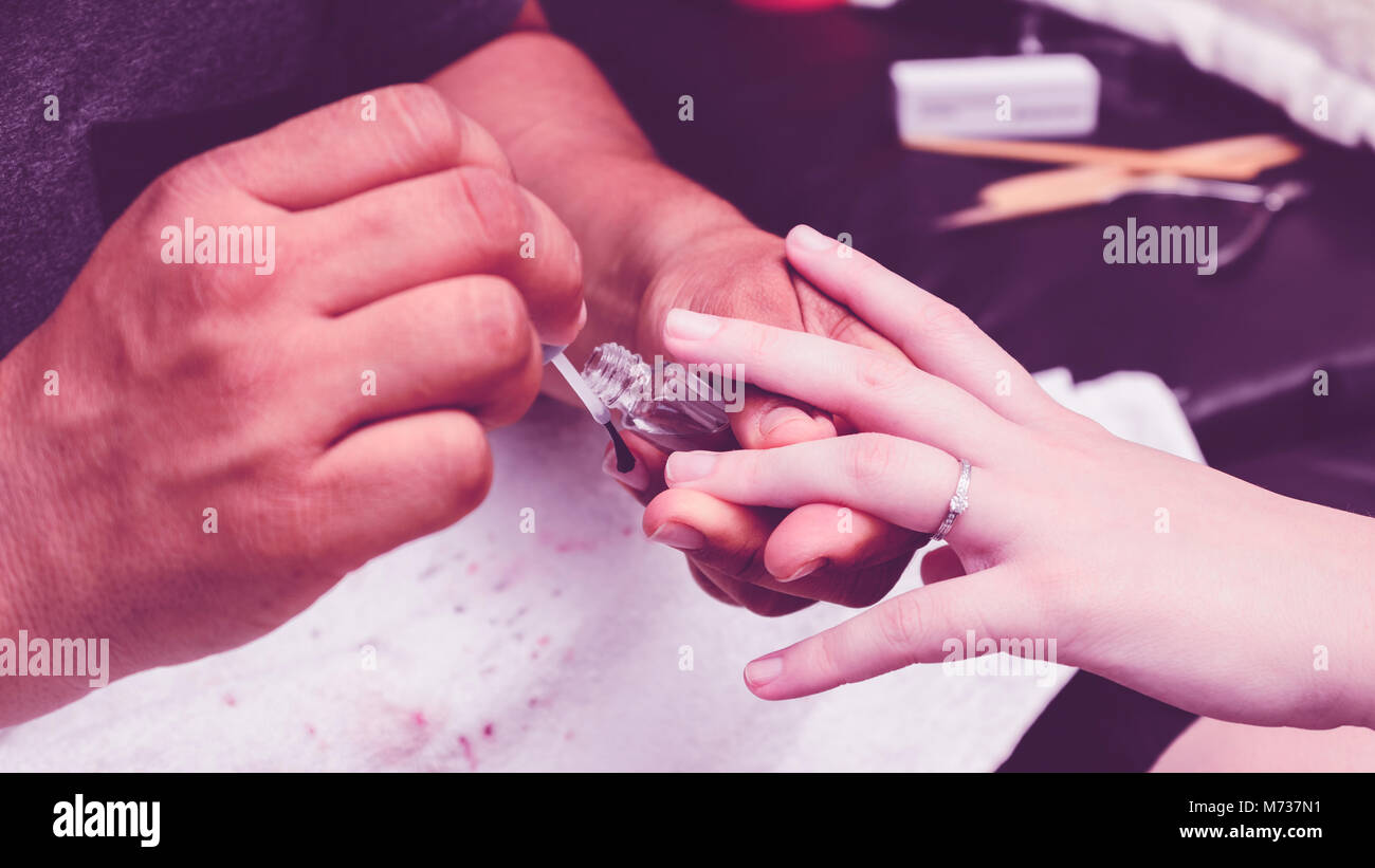 Maniküre, die eine transparente Basis auf die Frau die Hände vor der Nagellack lackieren. Stockfoto