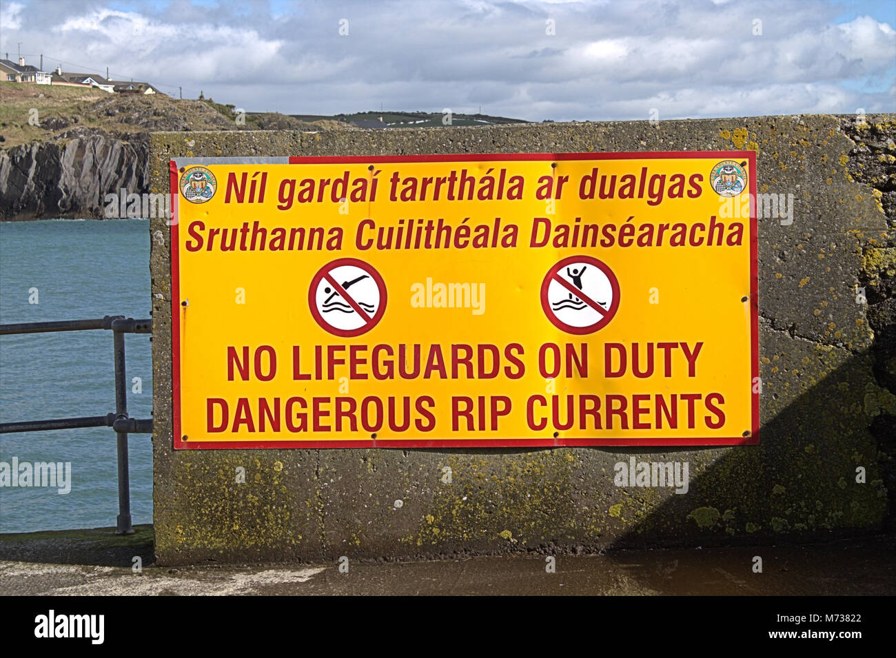 Gefahr Rip Gezeiten Zeichen in Englisch und Gälisch. Das Zeichen wird am Ende einer Anlegestelle in Rossbarbery, Irland, wo die Strömungen wirklich bewegen!! Stockfoto