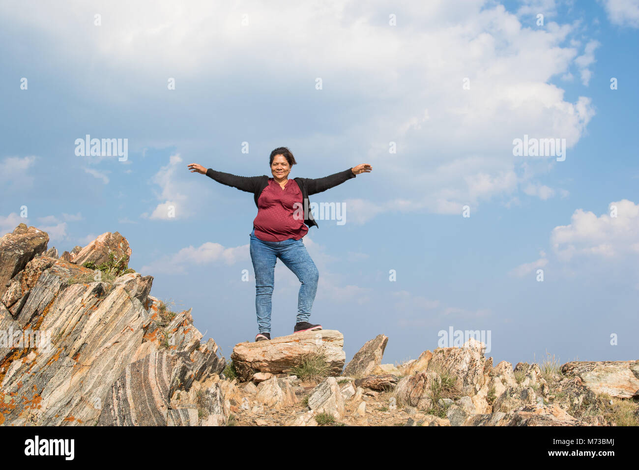 Eine asiatische Frau mit ihren Armen weit oben auf farbige Felsen Stockfoto