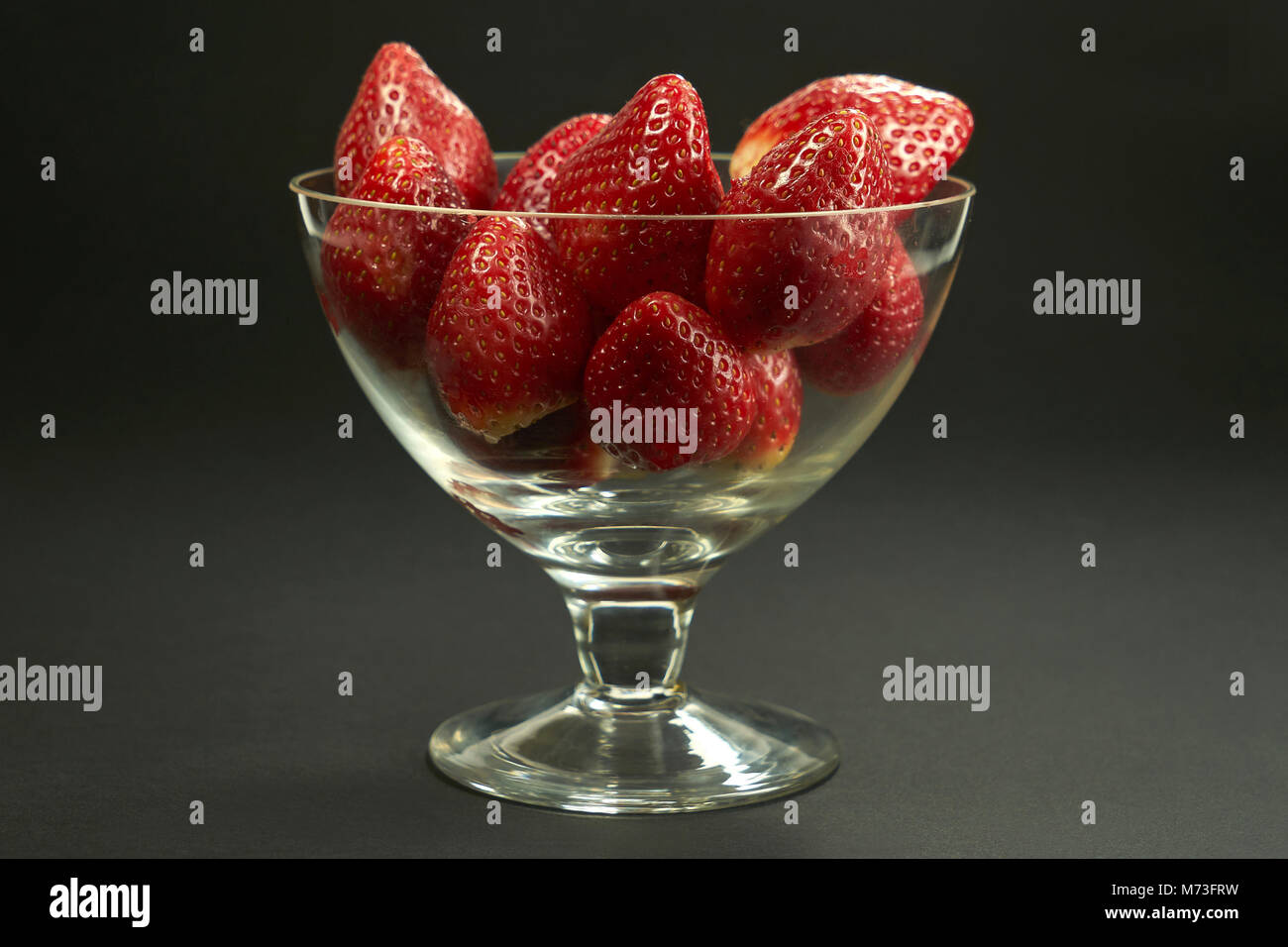 Erdbeeren in eine Glasschüssel auf schwarzem Hintergrund, Studio Stockfoto