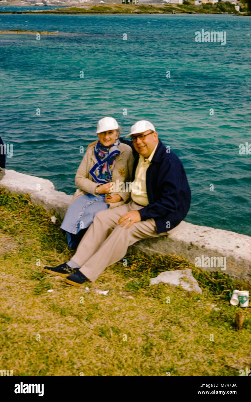 Ein älteres Ehepaar sich auf einem Stein an der Wand entlang der Kante, die von einem Körper von Wasser, 1955 gebaut. () Stockfoto