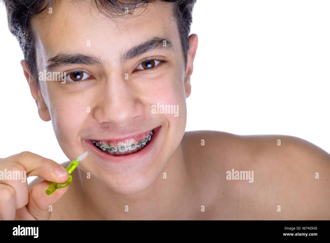 Cute Teenager mit weißem Hintergrund, das Tragen von Zahnspangen auf seine Zähne. Eine kleine Zahnbürste verwenden. Stockfoto