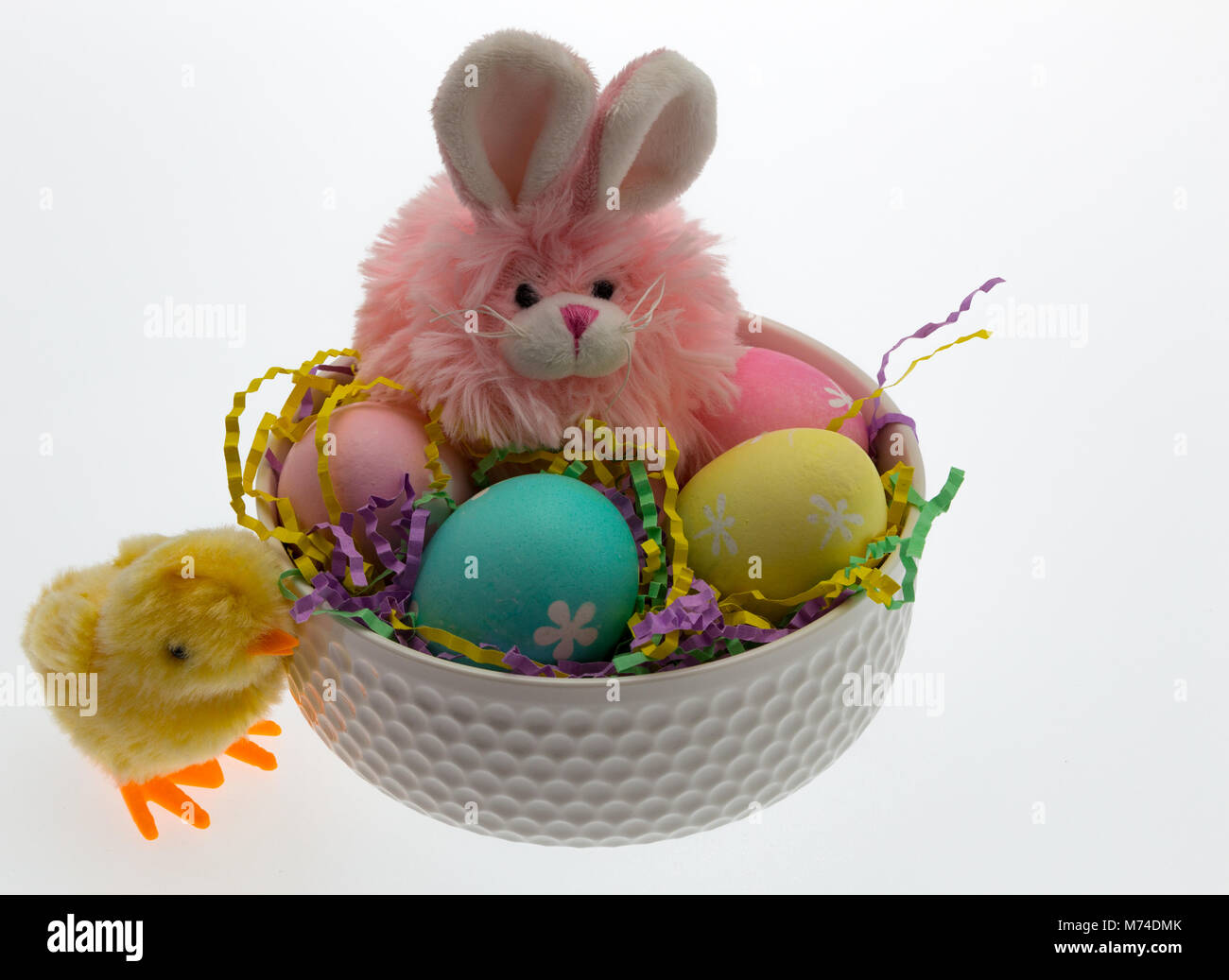 Rosa Osterhasen und mehrere Hand Eier in einer weißen Schüssel vermitteln ein Ostern Thema für Kinder gefärbt. Stockfoto