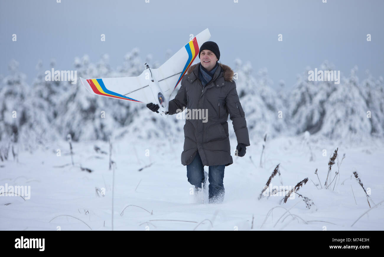 Glückliche Menschen gehen auf Schnee Winter mit rc-weißen Flugzeug Modell Stockfoto