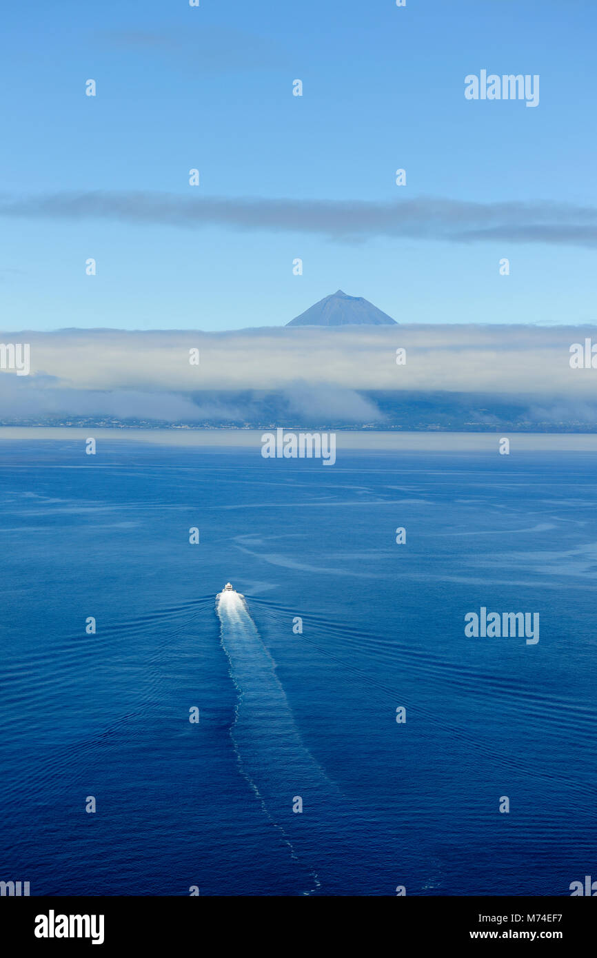 Ein Boot überquert die See zwischen der Insel São Jorge und Pico Insel am Horizont. Azoren, Portugal Stockfoto