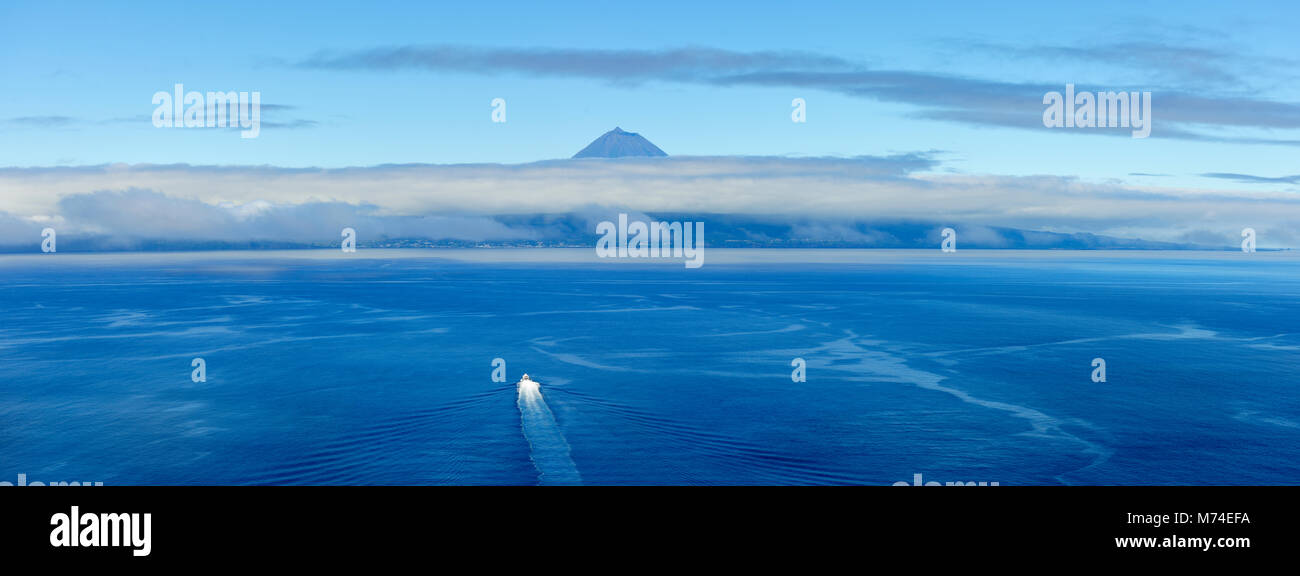 Ein Boot überquert die See zwischen der Insel São Jorge und Pico Insel am Horizont. Azoren, Portugal Stockfoto
