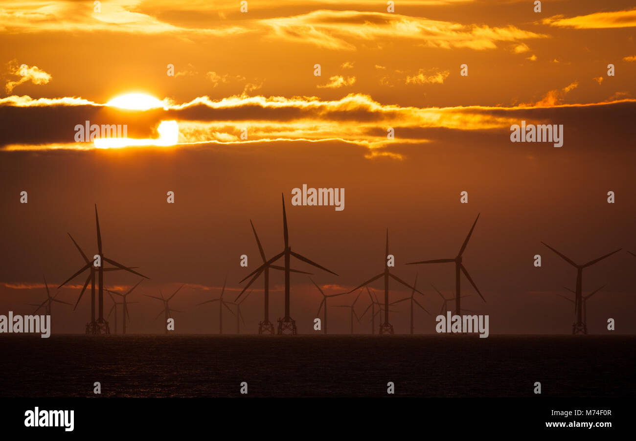 Sonnenuntergang über Windkraftanlagen in der Irischen See, Großbritannien Stockfoto