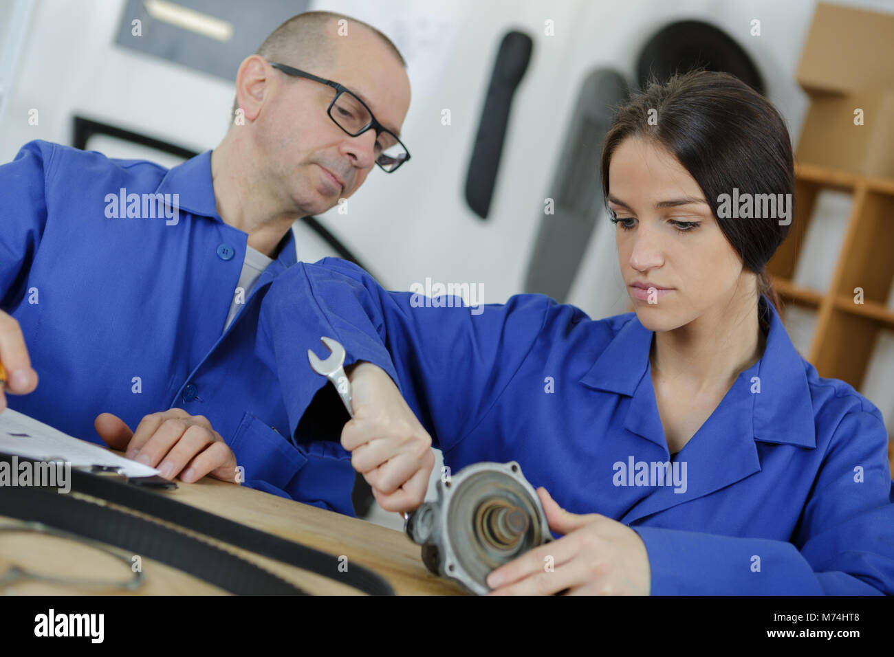 Weibliche Auszubildende mechanische Manipulation auto Teil mit Lehrer Stockfoto