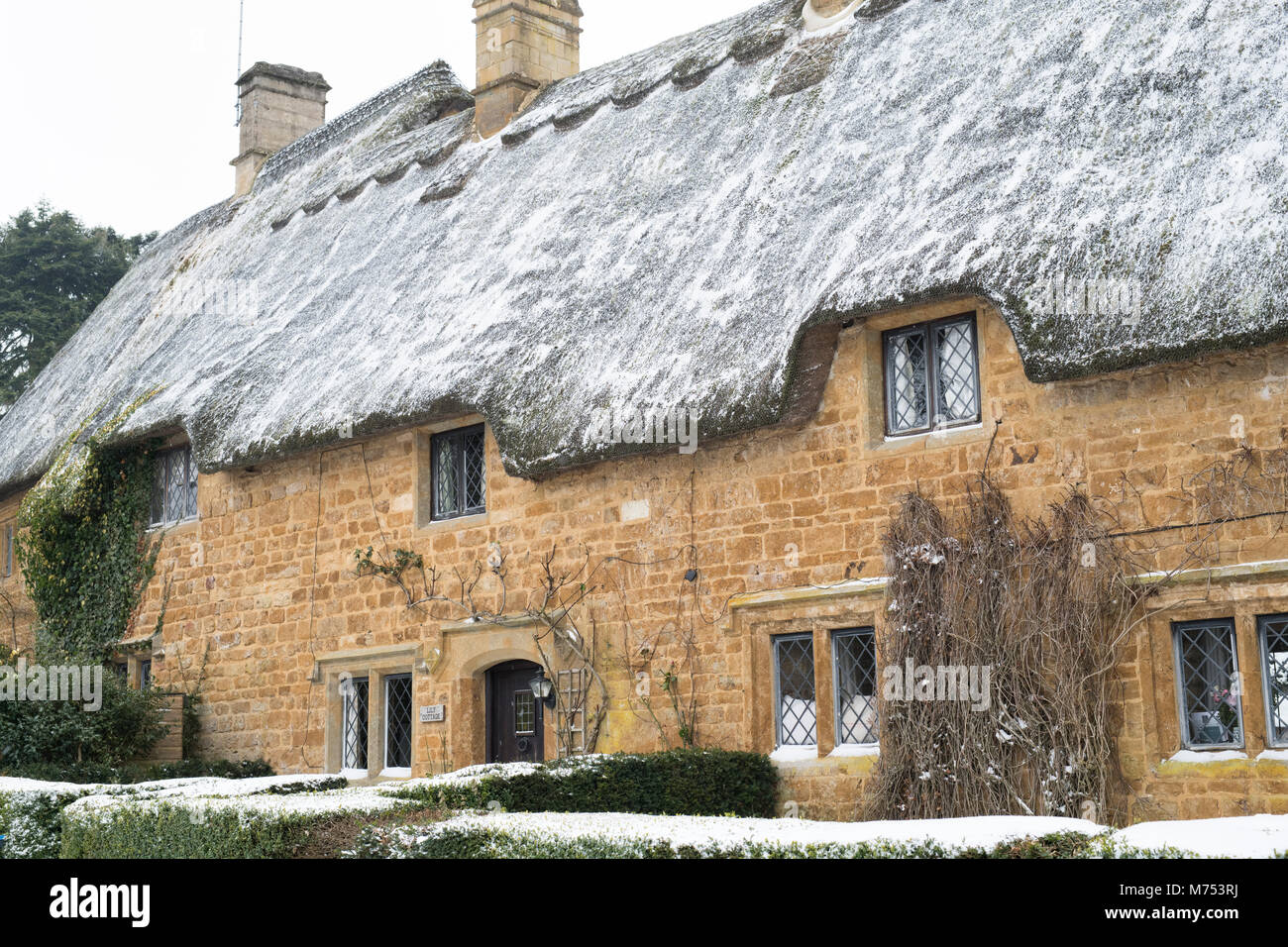 Strohgedeckten Steinhäusern im Winter Schnee. Große Tew, Cotswolds, Oxfordshire, England Stockfoto