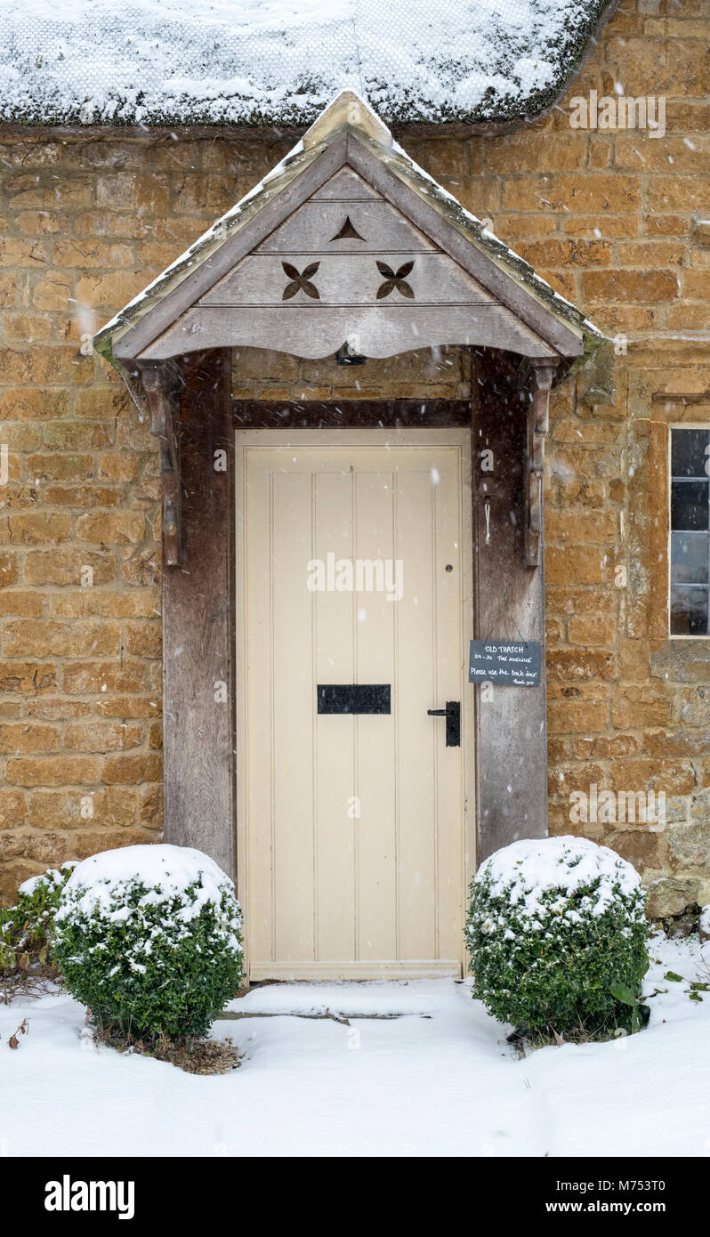 Reetgedeckte Ferienhaus aus Stein im Winter Schnee. Große Tew, Cotswolds, Oxfordshire, England Stockfoto