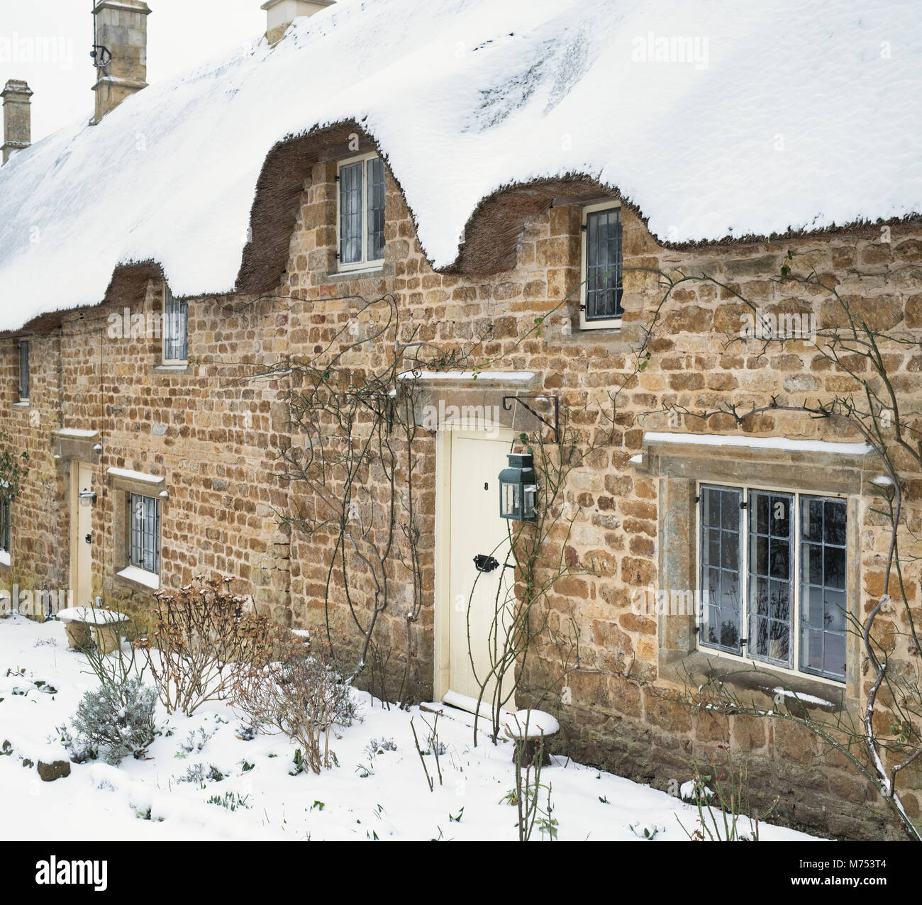 Strohgedeckten Steinhäusern im Winter Schnee. Große Tew, Cotswolds, Oxfordshire, England Stockfoto